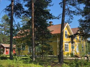 a yellow house with trees in the foreground at Hedenstugan B&B Hotel in Bergby