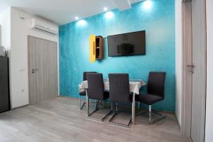 卡斯泰拉的住宿－Apartment Kala，一间设有桌子的用餐室和蓝色墙壁上的电视