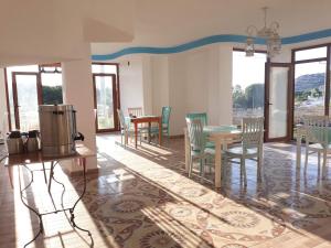 a dining room with a table and chairs and windows at ada kekiği pansiyon in Gokceada Town