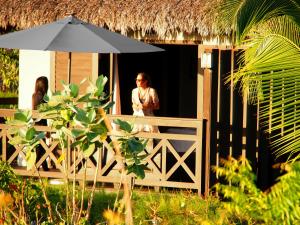 a woman standing outside of a house with an umbrella at Chic Hotel Boutique in Barra Grande