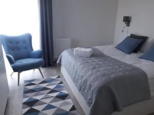 a bedroom with a bed and a blue chair at Apartamenty nad morzem & SPA BEST HOME 5 Mórz in Sianozety