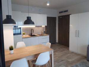 a kitchen with a wooden table and white cabinets at Apartamenty nad morzem & SPA BEST HOME 5 Mórz in Sianozety