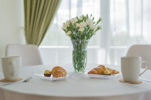 a table with two plates of pastries and a vase of flowers at Luxury Apartments in Druskininkai