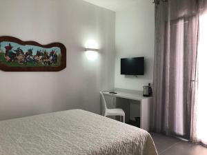 a bedroom with a bed and a desk with a television at White Asses Rooms in Castellammare del Golfo