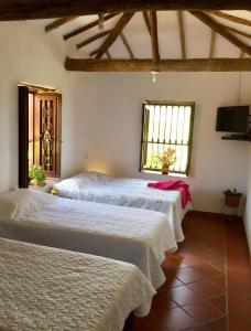 a bedroom with two beds in a room with windows at Aires del Sauzalito in Barichara