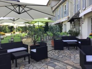 a patio with tables and chairs and umbrellas at Hôtel des Barrages in Brommat