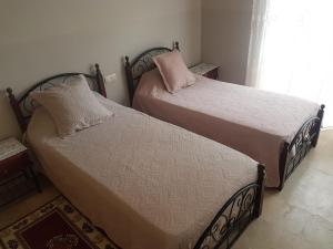 two beds sitting in a bedroom with a window at Mehdia plage in Kenitra