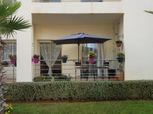 a house with a balcony with an umbrella and plants at Mehdia plage in Kenitra