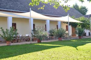 a white building with tables and umbrellas in a yard at Jackfall Apartman és Fogadó in Kisjakabfalva