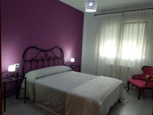 Dormitorio púrpura con cama y silla en Apartamento Las Hermanas, en Pontevedra