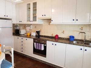 Una cocina con gabinetes blancos y un fregadero. en Apartamento Las Hermanas, en Pontevedra