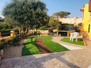 a garden with a white chair and a lawn at Appartamento Torre 82 in Torre Dei Corsari