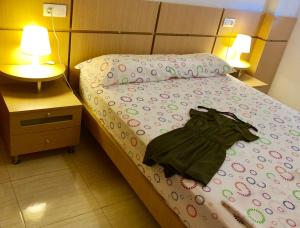 um quarto com uma cama com uma camisa verde em Marina D´or Asequible apartamento em Oropesa del Mar