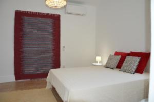 Un dormitorio con una cama con almohadas rojas y una ventana en Casa da Praia, en Carvoeiro