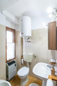 a white bathroom with a toilet and a sink at Fleurs De Neige in Pila