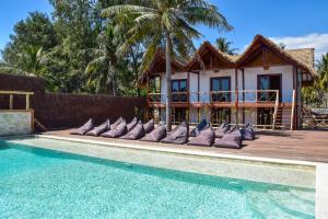 a villa with a swimming pool in front of a house at Mad Monkey Gili Trawangan in Gili Trawangan