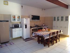 a kitchen with a table and a white refrigerator at Casa de Temporada Recanto Fazendinha in Olímpia
