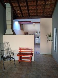 a bench and a chair in a room with a kitchen at Casa de Temporada Recanto Fazendinha in Olímpia