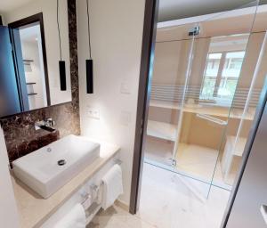 uma casa de banho com um lavatório e uma cabina de duche em vidro. em White Pearl Apartment 2.16 em Timmendorfer Strand