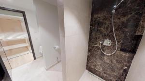 a bathroom with a shower with a stone wall at White Pearl Apartment 1.03 in Timmendorfer Strand