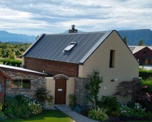 een huis met een grijs dak en een steen bij Charming Wanaka Cottage in Wanaka