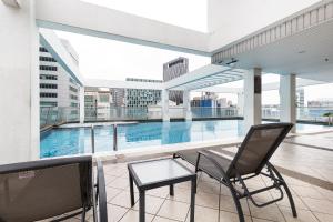 a balcony with a chair and a table and a pool at Parkview Suites KLCC by Airhost in Kuala Lumpur