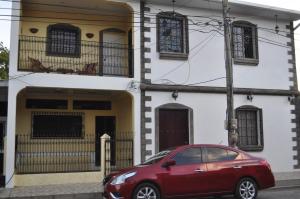 a red car parked in front of a house at Hotel Casa Blanca in León