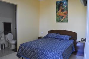 um quarto com uma cama com um edredão azul e um WC em Cuartos Casa Blanca em León