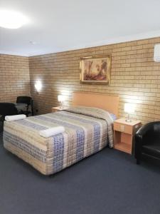 Habitación de hotel con 1 cama y 2 sillas en Macintyre Motor Inn, en Goondiwindi