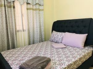 a bed with a black headboard and pillows on it at Luzville Residences - C5 in Naic