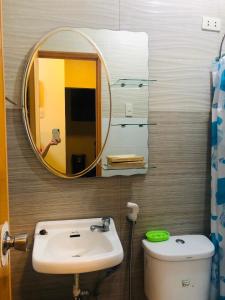 a bathroom with a sink and a mirror and a toilet at Luzville Residences - C5 in Naic