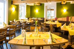 Landhotel Gutshof في Hartenstein: مطعم بطاولات وكراسي خشبية وجدران خضراء