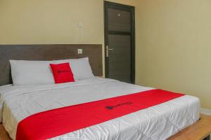 a bed with a red blanket on top of it at RedDoorz Syariah near Pasar Modern Cikopo in Karawang