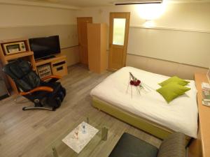 a room with a bed and a chair and a television at Hotel GOLF Hodogaya (Adult Only) in Yokohama
