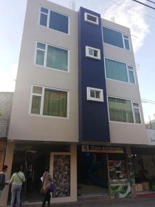 a tall building with people walking in front of it at Hotel La Cumbre in Baños