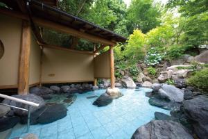 a pool of water with rocks and a building at Ogoto Onsen Yunoyado Komolebi in Otsu