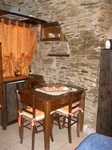 una mesa de madera con 2 sillas y una pared de piedra en Maison Mariot, en Roure Turin