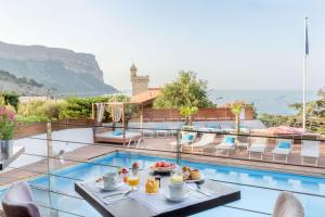 a hotel with a pool and a table with food on it at Best Western Plus Hôtel la Rade in Cassis