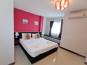 sypialnia z dużym łóżkiem z czerwoną ścianą w obiekcie บ้านธนาบูติคโฮเทล w mieście Surat Thani