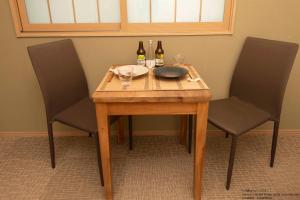 a wooden table with two bottles and two glasses at Stay SAKURA Kyoto Station South I in Kyoto