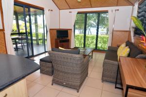 ein Wohnzimmer mit einem Sofa, Stühlen und einem TV in der Unterkunft Island Magic Resort Apartments in Port Vila