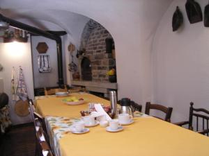 Roure TurinにあるMaison Mariotの黄色のテーブルクロスとカップが置かれたテーブル