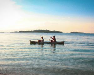 two men sitting in a canoe in the water at Billiton Ekobeach Retreat in Tanjungpandan