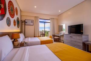 a hotel room with two beds and a flat screen tv at Bohol Shores in Panglao