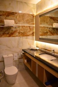 a bathroom with a toilet and a sink and a mirror at Nagoya Hill Hotel Batam in Nagoya