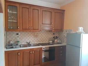 a kitchen with wooden cabinets and a white refrigerator at Apartma Opendoors Postaja in Most na Soči
