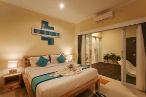 ein Schlafzimmer mit einem Bett mit einem Kreuz an der Wand in der Unterkunft Villa Julie & Villa Sydney, Seminyak - 2 Bedroom Modern Pool Villas! in Seminyak