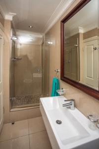 a bathroom with a sink and a shower with a mirror at Stay at The Point - Seaside Saunter in Durban