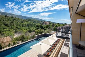 uitzicht op een zwembad met parasols bij Hôtel Sainte Victoire in Vauvenargues