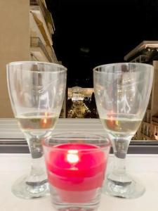 two wine glasses with a candle on a table at CosmosDome. Best view in the heart of Athens! in Athens